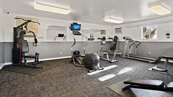 a gym with exercise machines and a tv on the wall